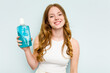© Asier - Young caucasian woman holding a mouthwash isolated on blue background happy, smiling and cheerful.