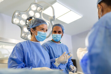 Canvas Print - Portrait of team of multiethnic surgeons at work in a operation theatre. Several doctors surrounding patient on operation table during their work. Team surgeons at work in operating room.