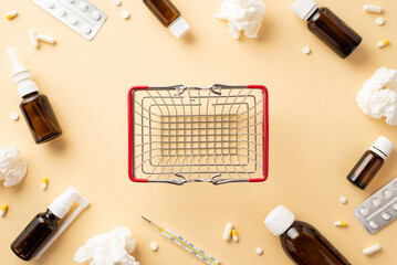 Wall Mural - Illness concept. Top view photo of empty shopping cart medicines transparent brown bottles pills blisters thermometer and crumpled paper napkins on isolated beige background