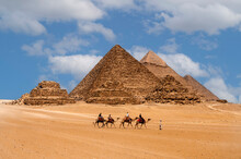 Cairo, Egypt. 08.25.2022. Group Of Tourists Riding Camels Seeing The Pyramids Of Menkaure, Chephren And Cheops.