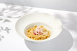Spaghetti with crab meat and cheese on white table with shadows. Seafood pasta with spaghetti and crab in summer italian menu Italian pasta with parmigiano cheese and crab meat