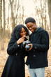 © prostooleh - Black couple walking in park and looking in camera in their hands