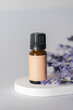 Amber bottle with craft label filled essential oil. Grey background with lavender flowers. Beauty concept for face and body care