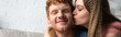 © LIGHTFIELD STUDIOS - pretty teen girl hugging and kissing cheek of redhead boyfriend in living room, banner.