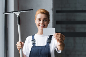 happy woman with window squeegee holding blank business card.