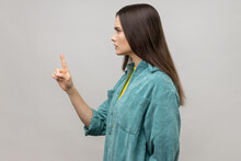 Be Careful! Side View Of Strict Bossy Woman Looking At Camera Seriously, Pointing Finger And Warning, Wearing Casual Style Jacket. Indoor Studio Shot Isolated On Gray Background.