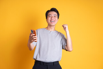 Wall Mural - Asian young man posing on a yellow background