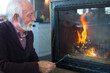 © Solid photos - Smiling senior man sitting by the fireplace in winter