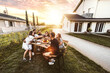 © Davide Angelini - Group of friends having fun at bbq outside dinner in home garden - Happy people cheering red wine sitting outdoor at dining table - Social gathering, youth, food and beverage concept
