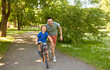 © Syda Productions - family, fatherhood and leisure concept - happy father teaching little son to ride bicycle at park