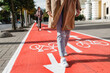 people, city and traffic concept - close up of woman's feet walking along separate bike lane or red road with signs only for bicycles on street