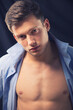 Portrait of handsome muscular young man wearing unbuttoned shirt