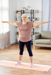 Poster - sport, fitness and healthy lifestyle concept - smiling senior woman exercising on mat at home