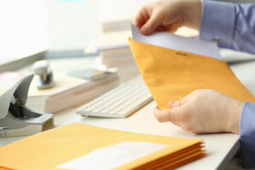 businessman takes out documents from yellow envelope
