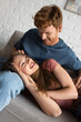 © LIGHTFIELD STUDIOS - redhead and smiling young man stroking hair of cheerful girlfriend in living room.