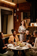 © Seventyfour - Happy young multicultural friends having chat by served festive table with homemade food and drinks while enjoying dinner at home party