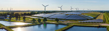 Environmentally Friendly Installation Of Photovoltaic Power Plant And Wind Turbine Farm Situated By Landfill.Solar Panels Farm  Built On A Waste Dump And Wind Turbine Farm. Renewable Energy Source.
