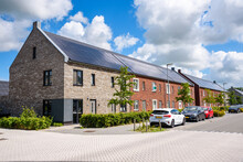 Row Of New Energy Efficient Brick Terraced Houses With The Rooftop Covered With Solar Panels On A Sunny Day