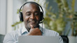 © Yuliia - Adult senior businessman african male expert supporter advisor working in assistance service company wears headphones hold distant negotiation with client teaching educational course online conference