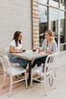 © Cavan - Wide shot of two young professional female having outdoor work meeting