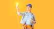 Female electrician with light bulb on yellow background