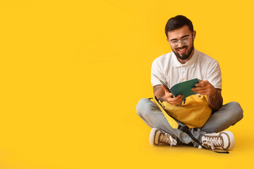 Poster - Handsome tattooed student with backpack on yellow background