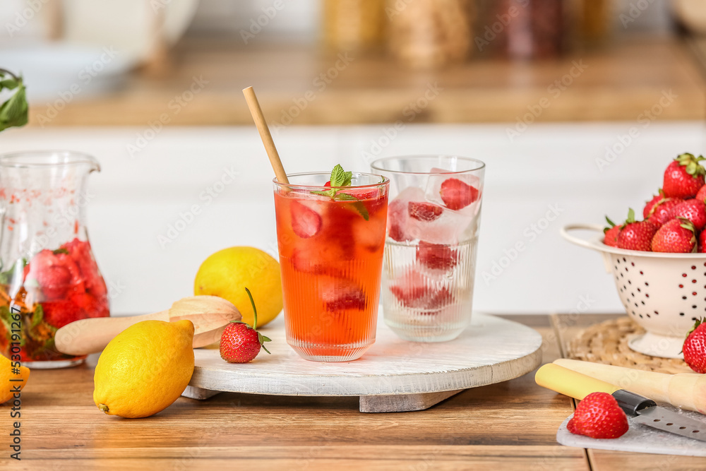 Tray with glass of cold strawberry lemonade on table in kitchen
