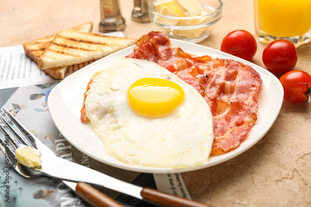 Plate with tasty fried egg and bacon on table