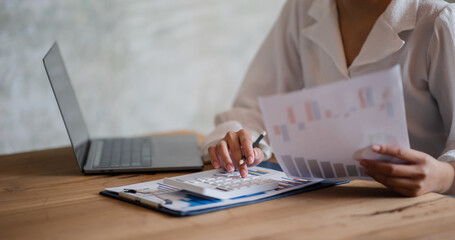 Wall Mural - Close-up of a woman's hand. She uses a calculator and laptop to write the numbers down. concept of accounting