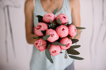 Wall Mural - Very nice young woman holding big and beautiful mono bouquet of fresh pink peonies, cropped photo, bouquet close up