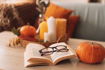 Autumn interior and holiday vibe with burning candles and pumpkin.