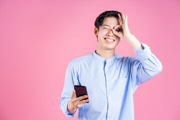 Wall Mural - Photo of young Asian man using smartphone on background