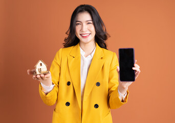 Young Asian woman holding concept house on background