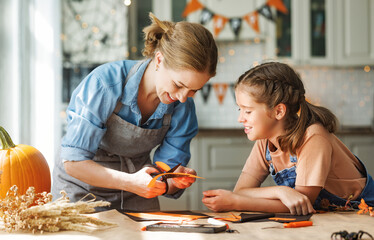 happy smiling family mother and daughter making halloween home decorations together