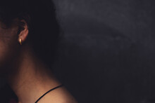 Bare Neck Of A Girl Wearing Golden Ear Ring Against Grey Background - Feminine Concept Image