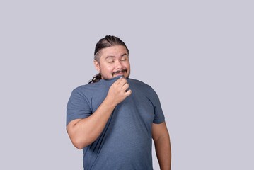 A man admires the good and fresh smell of his shirt. Result of fabric softener or scented detergent.