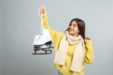 Canvas Print - Emotional woman with ice skates on light grey background