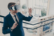 © VK Studio - Young businessman wearing virtual reality goggles working in office