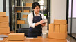 © Prathankarnpap - Smiling startup small business entrepreneur checking order and preparing parcel boxes for shipping to customer
