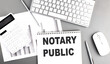 NOTARY PUBLIC text written on notebook on grey background with chart and keyboard , business concept