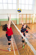 Four young sport women playing volleyball match in the sports gym