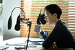 © Prathankarnpap - Young male radio host using condenser microphone recording voice at bright modern home studio