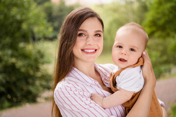 Wall Mural - Photo of charming cheerful mother little son dressed casual clothes hugging enjoying sunshine outdoors backyard