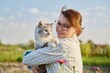 Outdoor portrait of middle aged woman with cat in her arms