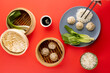 Overhead view of asian dumplings, soy sauce, endive, rice and chopsticks on red background