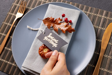 Wall Mural - Overhead view of thanksgiving place setting with caucasian woman holding greetings tag on slate