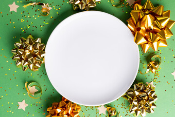 Image of christmas decoration with white plate and copy space on green background