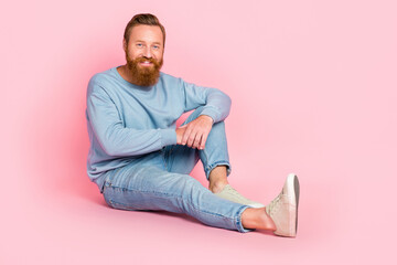 Wall Mural - Full body photo of satisfied friendly person sit floor toothy smile isolated on pink color background