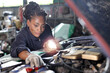 © feeling lucky - Woman technician car mechanic in uniform checking maintenance car service at repair garage station. Worker holding flashlight and wrench fixing breakdown vehicle. Concept of car center repair service.