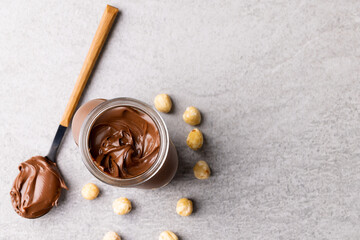 Wall Mural - Image of spoon with chocolate cream, jar and nuts on grey surface